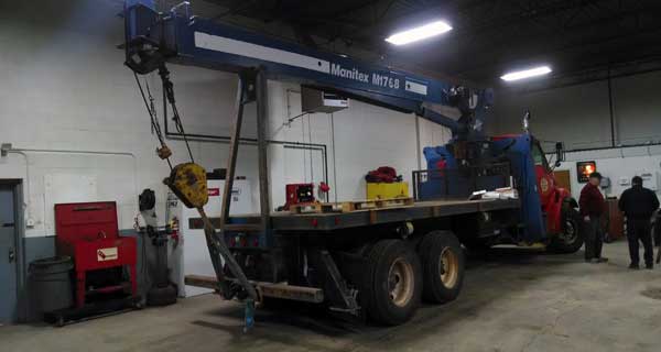 repairs and crane inspections being done on crane truck by service mechanics technians
